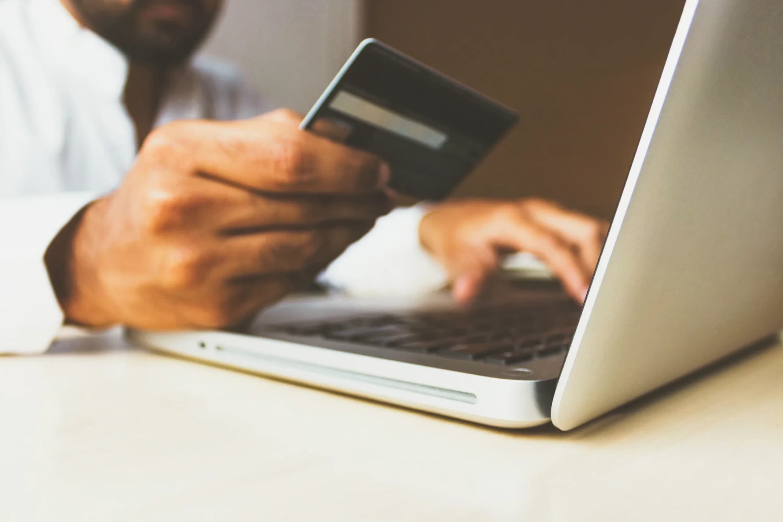 person holding a credit card whie typing on a laptop